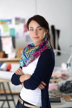 Güzel moda tasarımcısı stüdyoda duruyor.