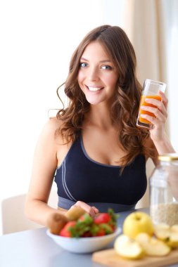 Mutfakta masada meyve suyu ve bardakla oturan bir kız.