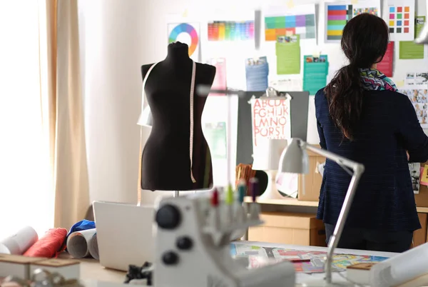 Güzel moda tasarımcısı stüdyoda duruyor.