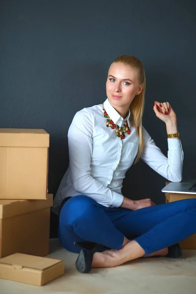 Mujer sentada en el suelo cerca de una caja con portátil —  Fotos de Stock