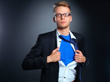 Genç işadamı hareket ve bir süper kahraman gibi gömleğini, yırtılma gri arka plan üzerinde izole