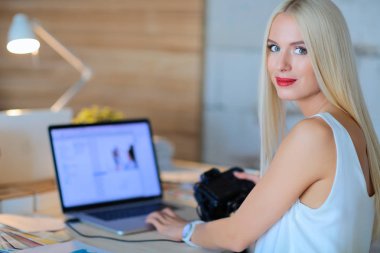 Moda tasarımcıları stüdyoda çalışıyor. Masanın üzerinde oturuyorlar.