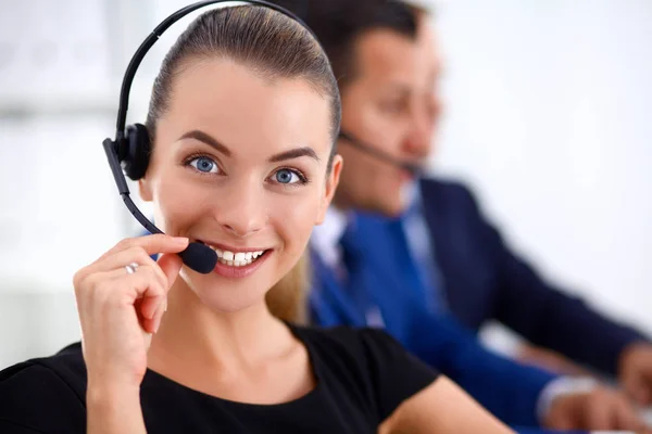 Portret van prachtige zakenvrouw in hoofdtelefoon lachend met collega's op achtergrond — Stockfoto