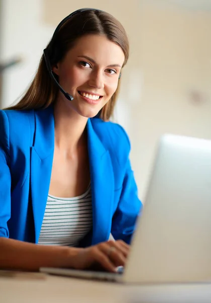 Porträt einer schönen Geschäftsfrau, die am Schreibtisch mit Headset und Laptop arbeitet — Stockfoto