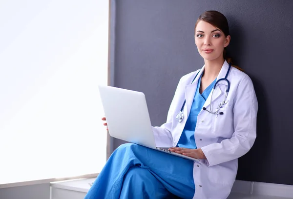 Female doctor working sitting on gray background — Stock Photo, Image