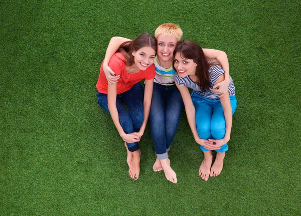 Three relaxing beautiful flirting women sit on green grass — Stock Photo, Image