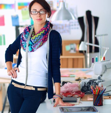 Güzel moda tasarımcısı stüdyoda duruyor.