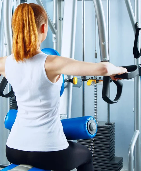 Hermosa chica en el gimnasio haciendo ejercicio en los entrenadores — Foto de Stock