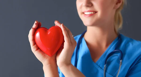 Joven doctora con estetoscopio sosteniendo el corazón — Foto de Stock