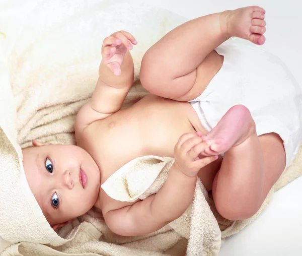 Hermosa niña tendida sobre una toalla beige — Foto de Stock