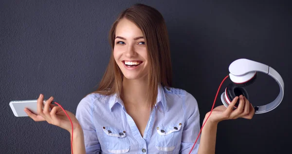 Lachende meisje met hoofdtelefoon zittend op de vloer in de buurt van muur — Stockfoto