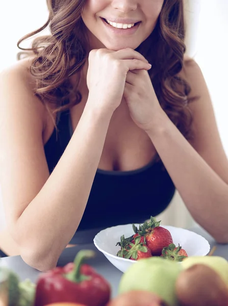 Chica sentada en la cocina en el escritorio con frutas y vasos con jugo — Foto de Stock