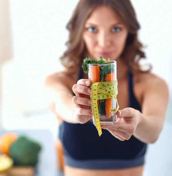 Woman holding a drinking glass full of fresh fruit salad with a tape measure around the glass — Stock Photo, Image