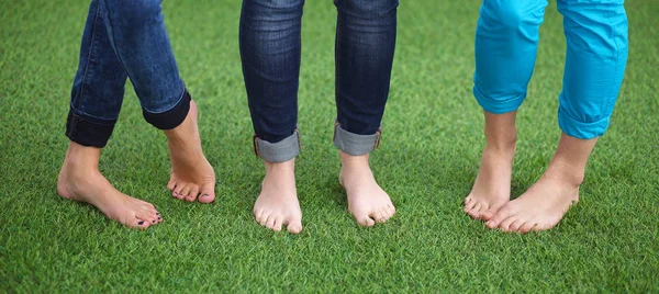 Tres mujeres con los pies desnudos de pie en la hierba — Foto de Stock