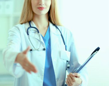 Hastane koridorunda klasörlü kadın doktor portresi.