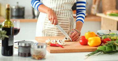 Mutfakta sebze doğrayan genç bir kadın.