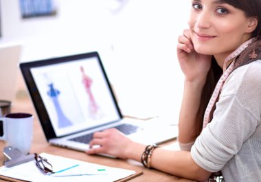 Ofis masasında oturan çekici kadın moda tasarımcısının portresi.