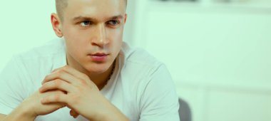 Genç adam sandalyede oturuyor.