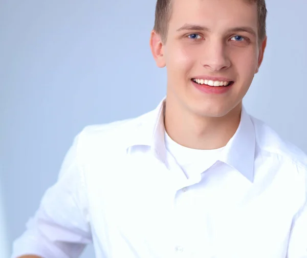 Portrait of young man smiling sitting on gray background — Stock Photo, Image