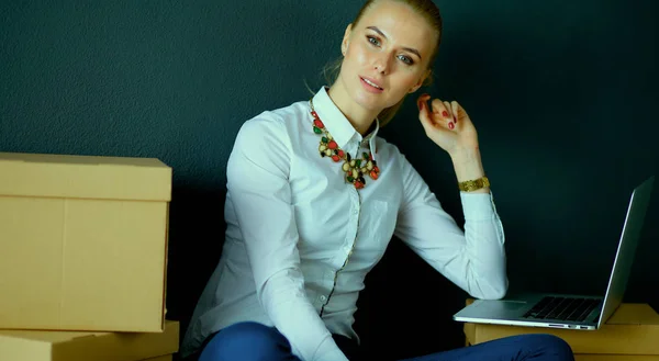 Woman sitting on the floor near a boxes  with laptop — Stock Photo, Image