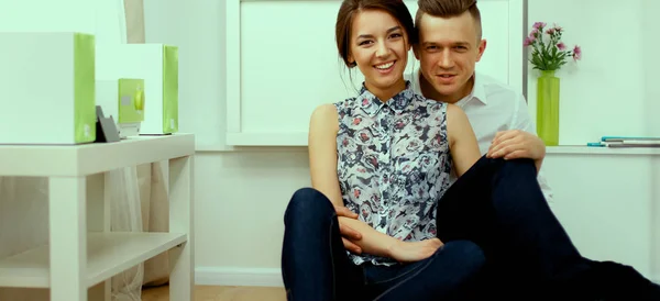 Glada unga par sitter tillsammans på golvet — Stockfoto