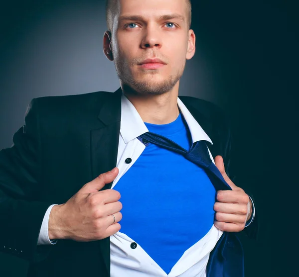 Młody biznesmen działający jak super hero i łzawienie koszulę, na białym tle na szarym tle — Zdjęcie stockowe