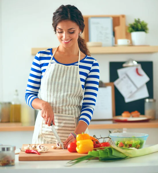 Jeune femme coupant des légumes dans la cuisine à la maison — Photo