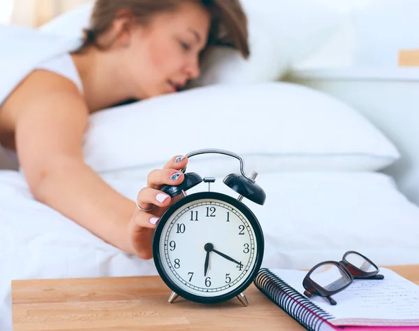 Una mujer joven apagando su despertador por la mañana — Foto de Stock