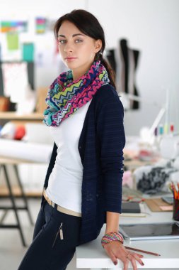 Güzel genç moda tasarımcısı stüdyoda duruyor.