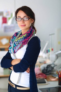 Güzel genç moda tasarımcısı stüdyoda duruyor.