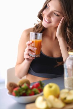 Mutfakta masada meyve suyu ve bardakla oturan bir kız.