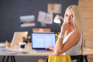 Moda tasarımcıları stüdyoda çalışıyor. Masanın üzerinde oturuyorlar.