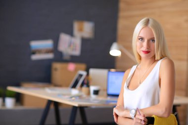 Moda tasarımcıları stüdyoda çalışıyor. Masanın üzerinde oturuyorlar.