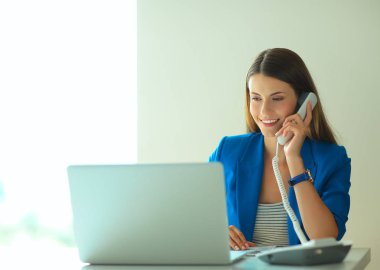 Telefon bir dizüstü bilgisayar önünde genç kadın portre