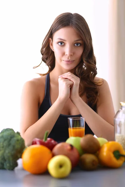 Девушка сидит на кухне на столе с фруктовым и стаканом сока — стоковое фото