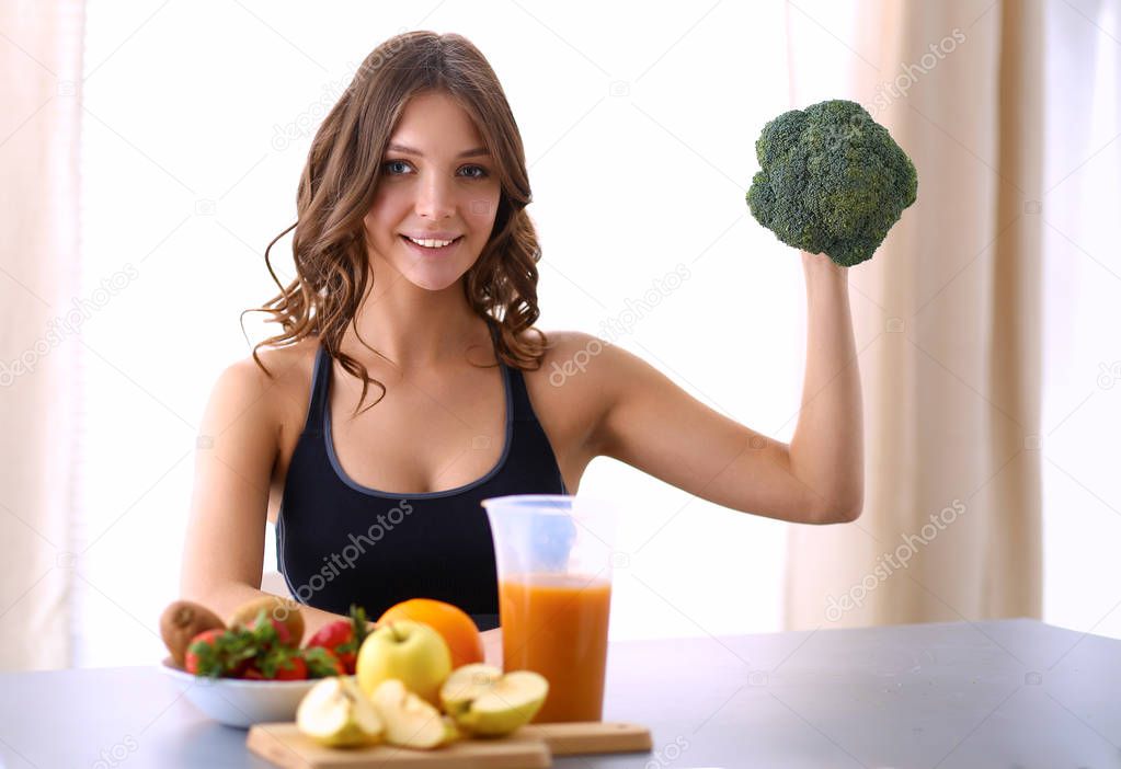 Girl sitting in kitchen on the desk with fruit and glasses juice
