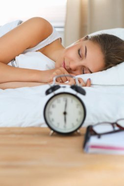 Güzel genç bir kadın, rahat ve mutlu bir şekilde yatakta uzanıyor.