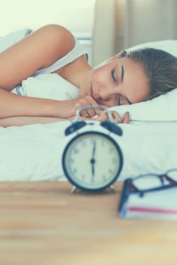 Güzel genç bir kadın, rahat ve mutlu bir şekilde yatakta uzanıyor.