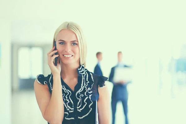 Mulher de negócios bonita usando telefone celular, de pé no escritório — Fotografia de Stock