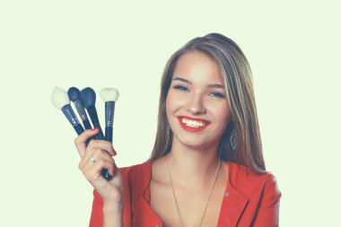 Genç güzel kadın elinde makyaj için fırça tutar