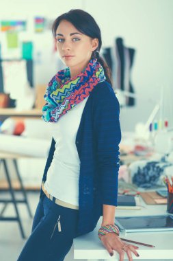 Güzel genç moda tasarımcısı stüdyoda duruyor.