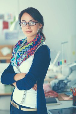 Güzel genç moda tasarımcısı stüdyoda duruyor.