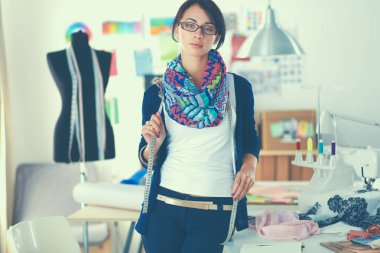 Güzel genç moda tasarımcısı stüdyoda duruyor.