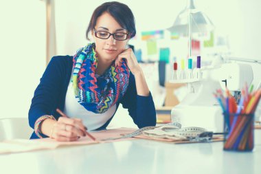 Genç terzi kâğıt üzerinde kıyafet deseni tasarlıyor.