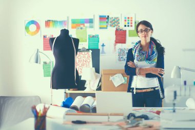 Güzel genç moda tasarımcısı stüdyoda duruyor.