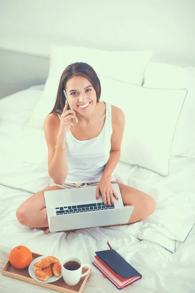 Jonge mooie vrouw zitten in bed met laptop — Stockfoto
