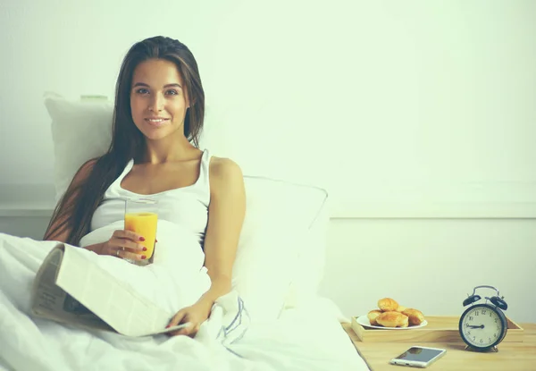 Beautiful young woman sitting in bed and having breakfast — Stock Photo, Image