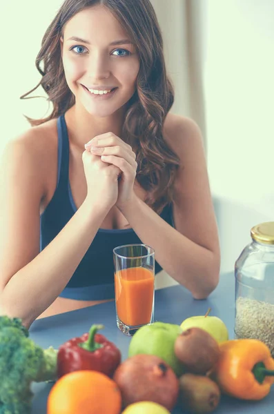 Chica sentada en la cocina en el escritorio con jugo de frutas y vasos — Foto de Stock