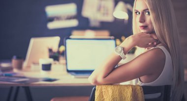 Moda tasarımcıları stüdyoda çalışıyor. Masanın üzerinde oturuyorlar.