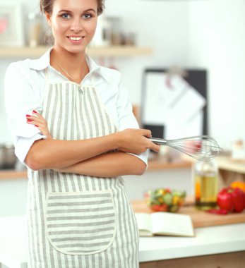 Mutfakta duran gülümseyen genç kadın.